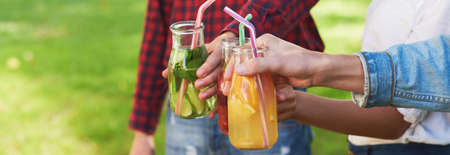 Healthy nutrition. Friends drinking fresh juice detox on green nature background. Youth lifestyle, vegetarian diet to go, fitness food, successful weight loss conceptの写真素材