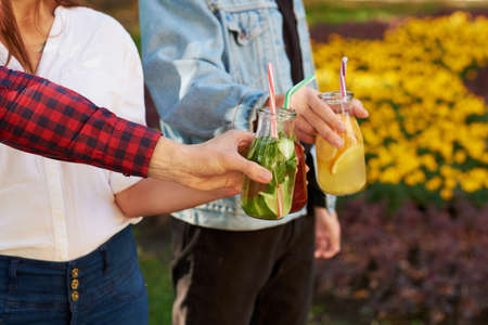 Healthy nutrition. Friends drinking fresh juice detox on green nature background. Youth lifestyle, vegetarian diet to go, fitness food, successful weight loss conceptの写真素材