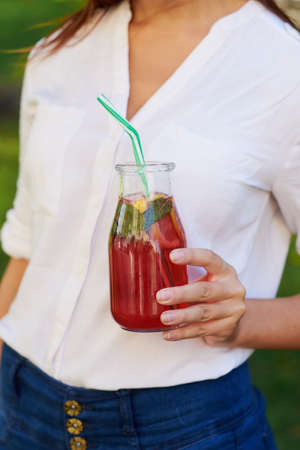 Healthy lifestyle. Unrecognizable young woman with yellow berry detox smoothie in summer, on green nature background. Diet, well being and weight loss conceptの写真素材