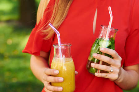 Healthy lifestyle. Unrecognizable young woman with fruit detox smoothie in summer, on green nature background. Diet, well being and weight loss conceptの写真素材