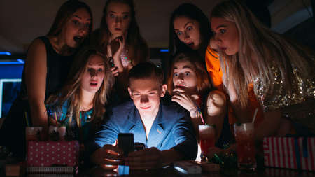 Surprising Christmas pictures on mobile phone. New Year miracle, females attention for young male. Night club background, amazing leisure time, surprise conceptの写真素材