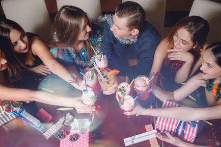 New Year celebration top view. Love couple at Christmas party, happy friends company with cocktails. Club background, romantic moodの写真素材