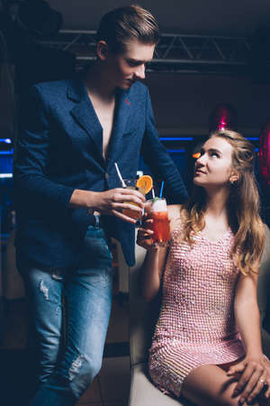 Flirty relationships. Night club party background. Modern stylish youth, romantic atmosphere with drinks, seduction conceptの写真素材