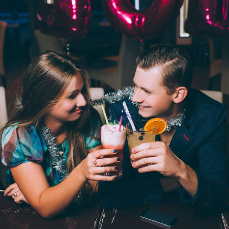 Happy couple at New Year party. Romantic date with cocktails, joyful leisure time. Night club background, festive mood, relationship conceptの写真素材