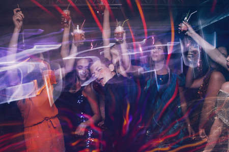 Happy company on dance floor. Joyful New Year in night club, active Christmas celebration in motion. Disco party in blurred colors, modern youth life, pickup conceptの写真素材