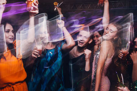 New Year dance party in motion. Happy friends company in night club, active Christmas celebration. Disco people in blurred colors, modern youth life, pickup conceptの写真素材