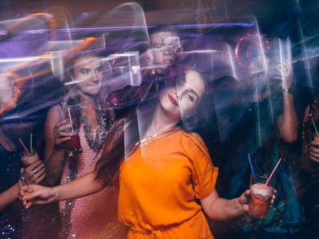 Disco party in night club in blurred motion. Happy friends dancing at Christmas celebration, active New Year company, modern youth lifeの写真素材