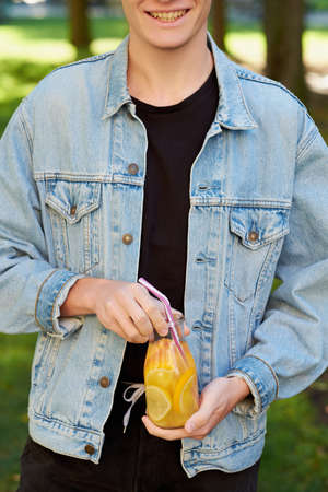 Healthy youth lifestyle. Happy hipster guy with detox with sweet citrus detox tea or orange juice in...
