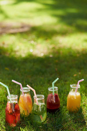 Healthy detox colourful drinks on green summer grass. Natural, fresh, organic juices and tea in bottles. Diet, well being and weight loss, superfoods, health, vegetarian food conceptの写真素材