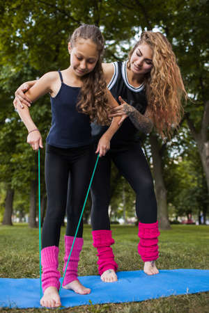 Active teenage sport. Family training exercise. Teamwork gymnastics with coach, healthy beautiful lifestyle. Nature background, creative entertainment outdoorsの写真素材