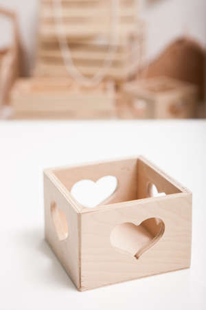 Close up wooden box with heart shaped hole on white table. Handmade classic properties for floristics workshop, floral arrangement, presents and decoration conceptの写真素材