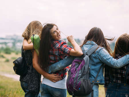 Friendly hugs admire nature tourism concept. Travelers group unity. Smiling girl look back.の写真素材