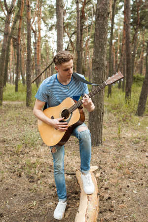 Pensive man playing guitar forest concept. Alone on the nature. Lifestyle of artist.の写真素材