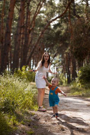 Happy mother baby bubble blowwing nature concept. Family moments. Sunny day in the forest.の写真素材
