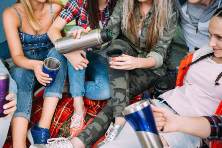 Friends group get warm with tea in the tent. Picnic time.の写真素材
