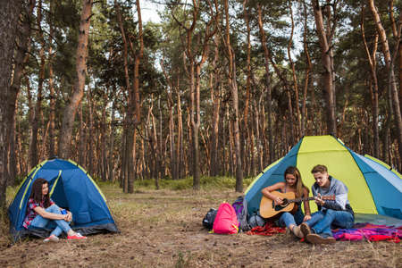 Friends listen guitar music. Tourist rest on nature. Camping lifestyle