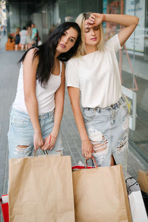 Tired women after long shopping. city stores concept. Exhausting purchases. Shopaholic lifestyle.の写真素材