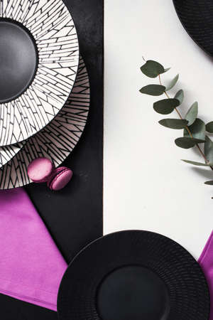 Fancy plates on black and white background. Creative restaurant table setting with flowers and...