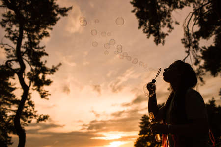 Woman bubble blowing silhouette nature concept. Unity with the nature. Traveler leisure.の写真素材