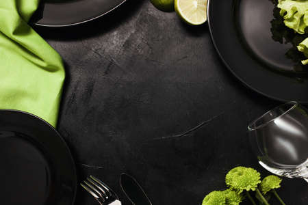 Plates and cutlery on black background with contrast green color. Creative fancy restaurant table setting. Art and design conceptの写真素材
