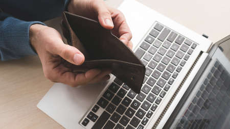 Internet scam. Fraud danger online. Man holding an empty wallet because he lost his money to a...