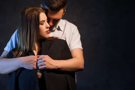Man hugging embracing a woman wearing his jacket. Family couple love protection and care concept
