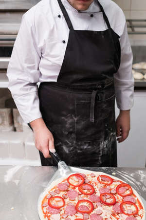 Chef cooking pepperoni pizza and prepared to put it in the oven. Simple yet delicious traditional italian mealの写真素材