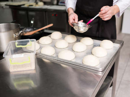 It is where a burger begins. A cook greasing hamburger rolls before putting them in the oven and...