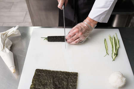 I bet it tastes delicious. Chef cuts sushi rolls prepared from fresh ingredients - rice nori salmon and cucumber.の写真素材