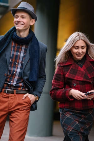 Stylish young couple walking in the city. Fashion trends. Youth casual lifestyle. Young girl and man smiling, happy togetherの写真素材