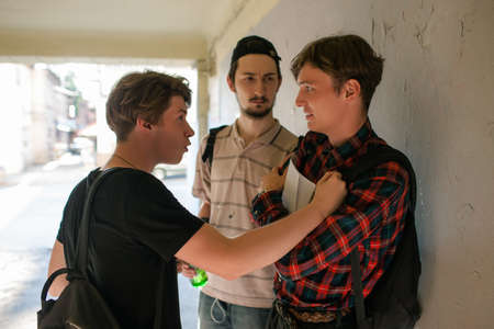 scared smart boy is attacked by thugs. threat to be beaten up by street gang. teenage violence conceptの写真素材