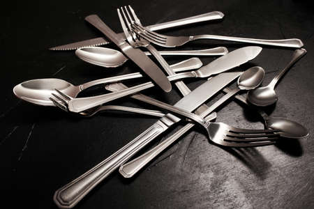 Silver cutlery on black background. Dishes cleaning after a party concept