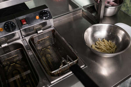 French fries - best junk food ever. Cook preparing fast food in the restaurant kitchen. Unhealthy and unbalanced eating conceptの写真素材