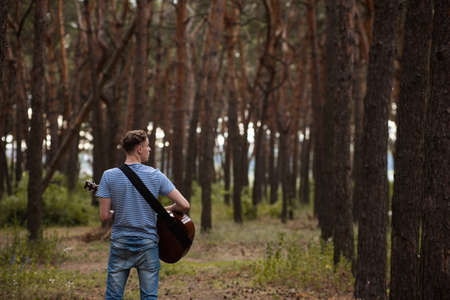 Talented guitarist playing forest hiking concept. Happiness of the artist. Unity with the nature.の写真素材