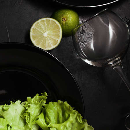 Plates and wine glass on black background with contrast green color. Fancy restaurant dining. Art and design conceptの写真素材