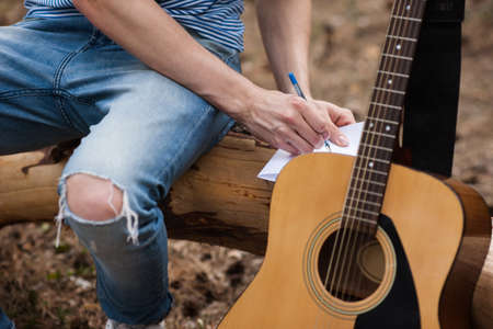 Guitar advertisement forest man idea concept. Creating masterpiece lyrics. Working process.