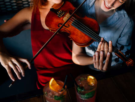 man teaching girl to play violin. classical instrument tutor. sharing experience. help support education improvement conceptの写真素材