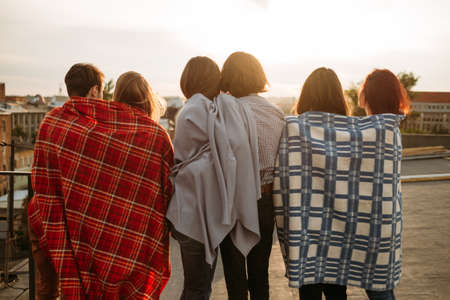 Romantic relationship. Love and dating. Back view of diverse young couples hanging out together on a rooftopの写真素材