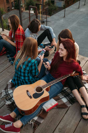 Young friends looking at their smartphones. Social media addiction. Modern teenage problems. Need of sharingの写真素材