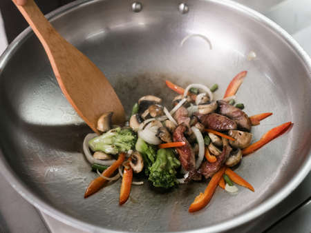 Asian cuisine meal at a restaurant. Meat and vegetables dish is cooking in wokの写真素材