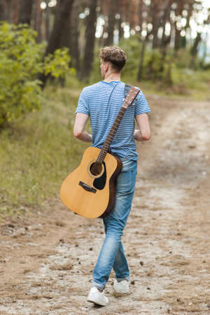 Talented guitarist playing forest hiking concept. Happiness of the artist. Unity with the nature.の写真素材