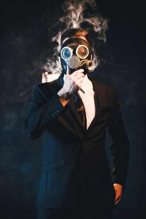 Man covered in smoke and wearing a gas mask. Dangerous influence of smoking addiction. Health hazard conceptの写真素材