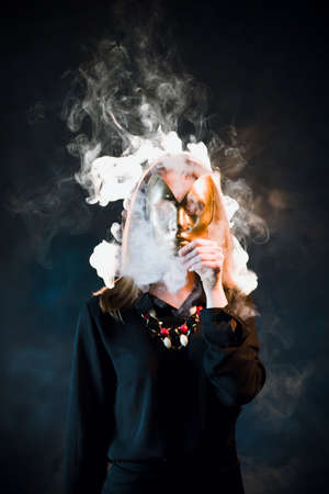 Woman covering her face with a mask surrounded by nicotine fumes. Danger of being passive smoker conceptの写真素材