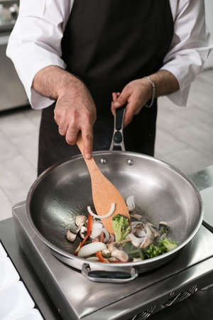 Chef showing off his professional skills. Cooking master at work in restaurant kitchen. Vegetables and meat mixing in the air techniqueの写真素材