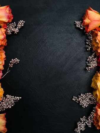 Orange and red autumn roses dark background with silver beads adornment. Symbol of deep feelings and elation. Copyspace conceptの写真素材