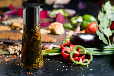 Natural organic oil and spices in a bottle with vegetables in the background. Meal seasoning and traditional condiments conceptの写真素材