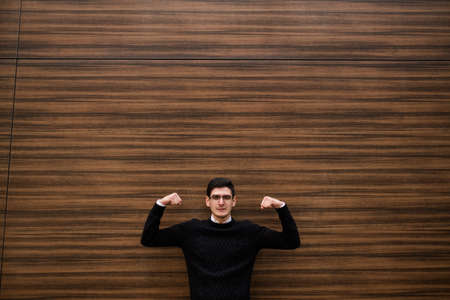 strong business solutions. development strategy. office corporate man showing his strength with hand gesture. wood texture wall background. outdoors street. free space conceptの写真素材
