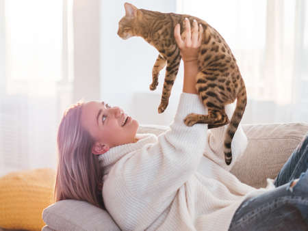 love human and animal relationship. furry friend. cuddling time. girl holding her kitty high in the air.の写真素材