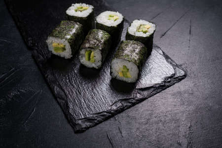 sushi rolls with salmon covered in nori on dark background. Japanese restaurant menu. Delicious traditional eastern foodの写真素材