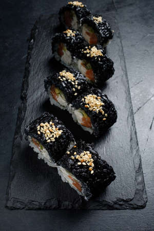 black sushi rolls on dark background. Japanese traditional food preparing craft and creative modern food artの写真素材